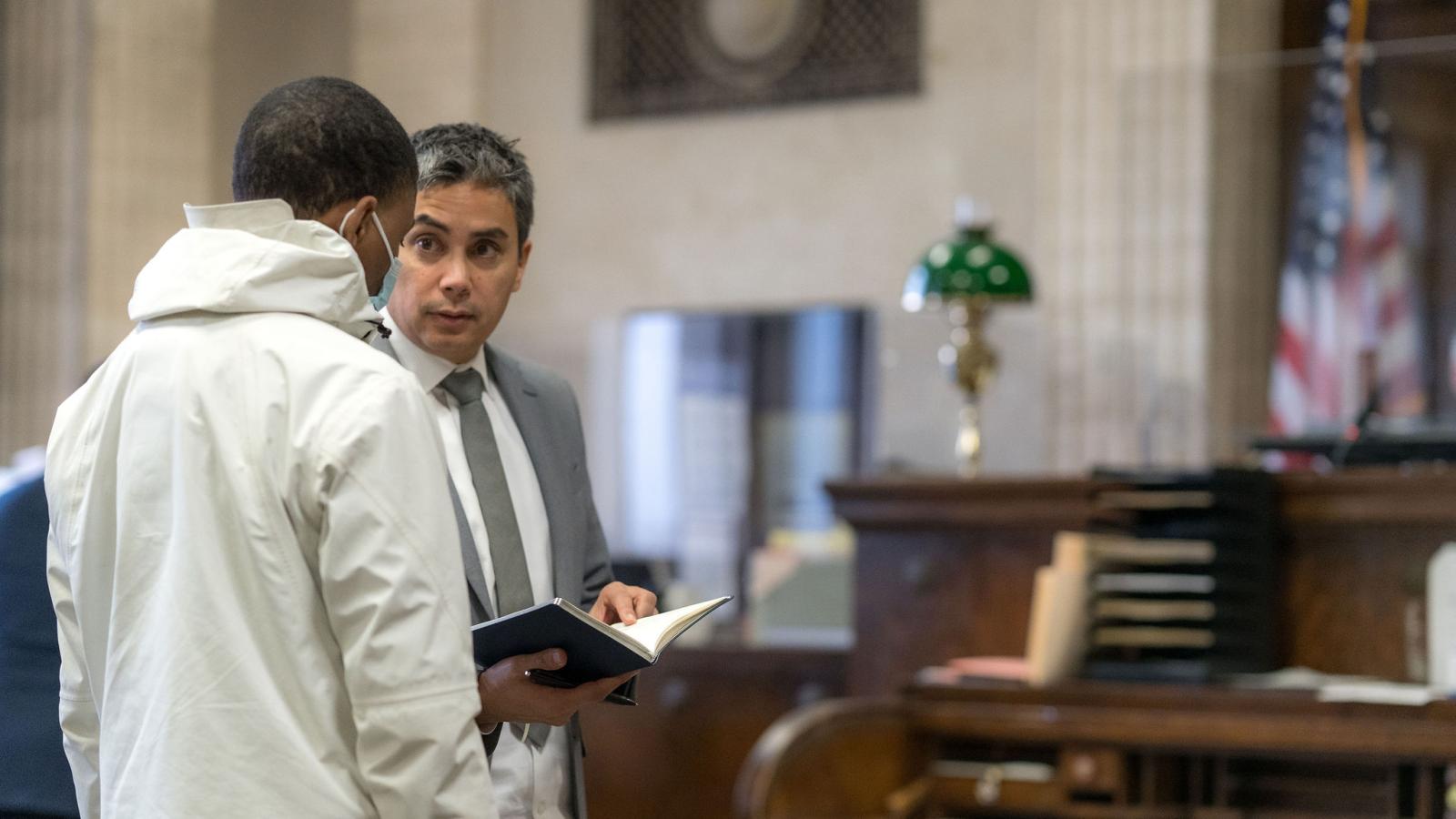 Assistant Public Defender consults with his client in a courtroom